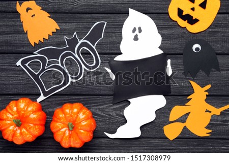 Halloween paper decorations with orange pumpkins on black wooden table