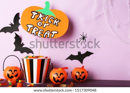 Text Trick or Treat with candies and pumpkin buckets on purple background
