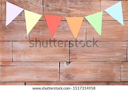 Colorful paper flags hanging on brown wooden background