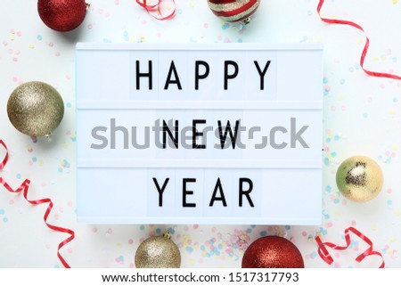 Lightbox with words Happy New Year and christmas ornaments on white background