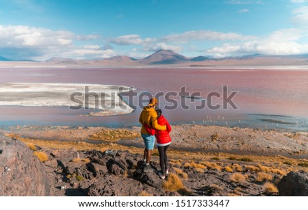 Couple with Red Lake landscape, Bolivia. Beautiful coloured water, with mountain background, and unique scenic view. Flamingos in the lake. Shot in Uyuni, Salar de Uyuni, South America. Couple in love