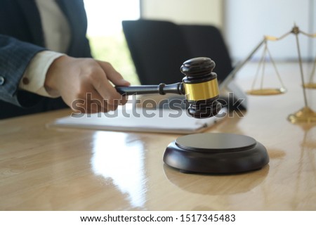 Concept of justice, Lawyer holding a hammer pretending to hit on a wooden tray put on the desk.