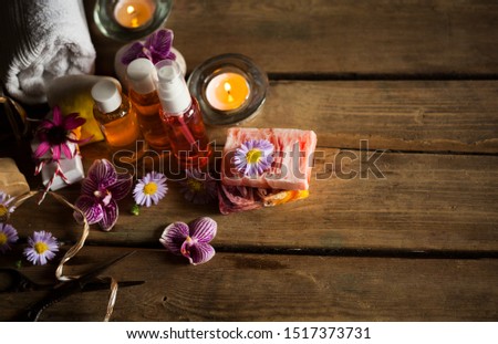 Natural spa products and decor for bath. Handmade herbal soap, organic oil, orchid flowers,sea stones,candles and gift boxes on wooden desk, layout photo.