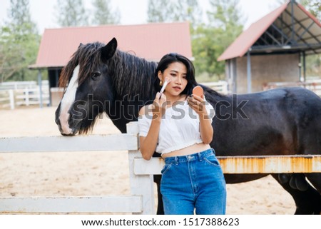 Girl doing makeup in front of a horse.