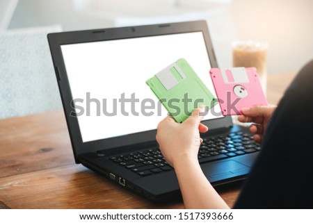 Closeup of girl hands holding floppy disk old technology used to save data. she try to use them with laptop