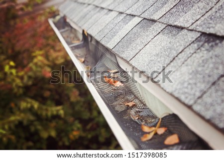 Plastic guard over gutter failure on a roof with leaves stuck in the mesh Royalty-Free Stock Photo #1517398085