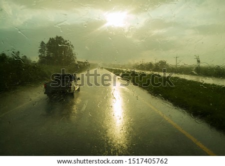 Driving on rainy road view through bus inside with rain fall on glass panes