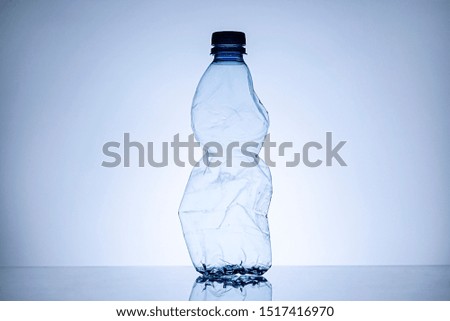 Side border with copy space of a crumpled empty clear plastic bottle standing upright in a concept of disposable household waste and pollution