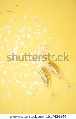 Champagne glasses with gold confetti, glitter yellow background. new year celebration. Top view. The concept of celebration.