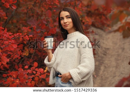 Woman photographer drinking coffee walking in the red foliage autumn forest