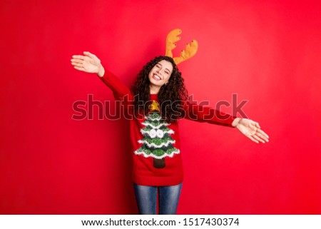 Photo of pretty curly lady with open palms meeting relatives at x-mas family gathering need much hugs wear head horns knitted pullover isolated red color background
