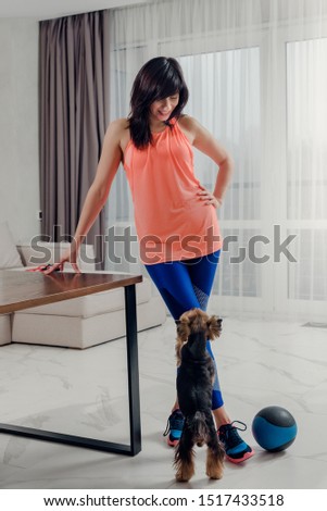 Young woman in sportswear playing with dog while having break
