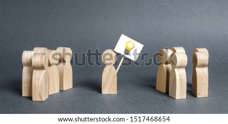 A man with a poster with a picture of the idea bulb refers to a crowd of people. The concept of proposing a new idea and option, a fresh look at the problem and finding a solution. Ambition Royalty-Free Stock Photo #1517468654