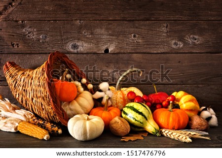 Thanksgiving cornucopia filled with autumn pumpkins and vegetables against a rustic dark wood background Royalty-Free Stock Photo #1517476796