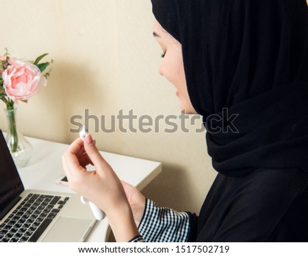 Close-up photos of hijab women listening to music using modern wireless ear phones facing the camera while laughing