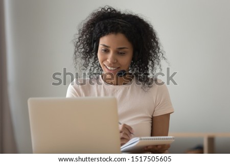 African woman interpreter in headset working from home online translation job, girl improve foreign language skills look at pc learns repeat words memorizes them, do task use internet website concept Royalty-Free Stock Photo #1517505605