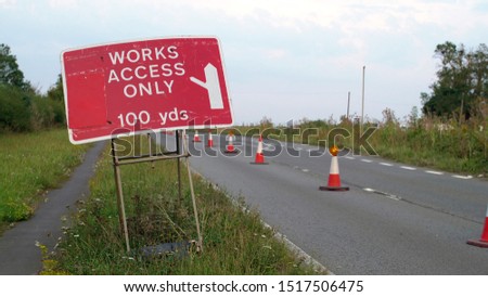 works access only sign next to roadworks cones flashing on UK motorway at evening with traffic passing