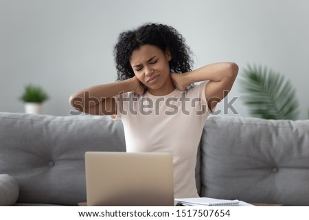 Mixed-race 30s woman touching massaging neck to relieve severe ache suffers from strong pain after long time using of laptop without break, incorrect posture or inactive sedentary lifestyle concept Royalty-Free Stock Photo #1517507654