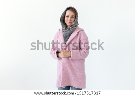 Cheerful young slim woman posing in pink coat with hood over white background. Concept of love for stylish unique things.