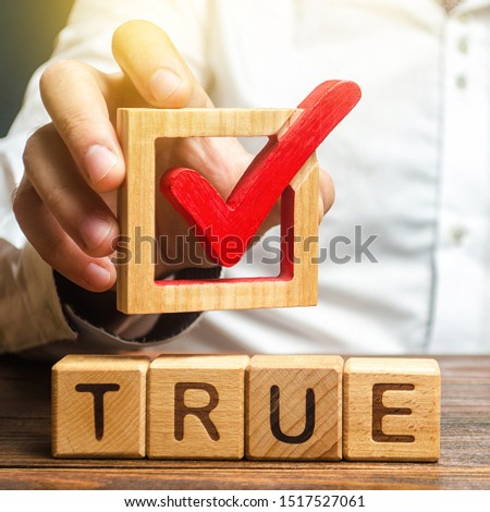 A man holds a red check mark over word True. Confirm the veracity and truth. Fight against fake news hostile propaganda. Confirmation facts, refutation of rumors. Debunking Myths and Misconceptions Royalty-Free Stock Photo #1517527061