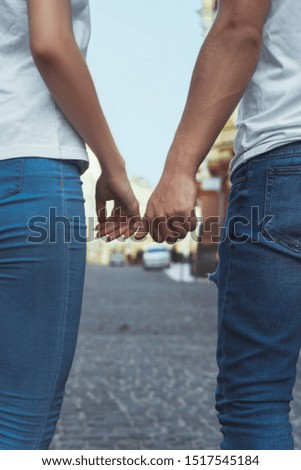 A pair of lovers in the city. Couple holding hands on the street. Girl and guy in jeans and white t-shirts. Romantic picture.together in the city