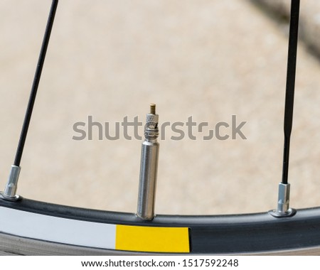 Closeup detail of bicycle tire valve stem in the "closed" position on a road bike wheel.
