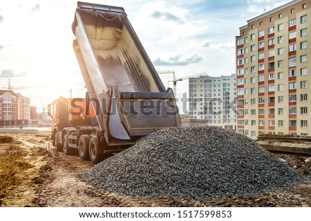 Construction truck tipping dumping gravel on road construction site,tip truck and ripper at work preparing ground for new housing estate,Dump truck unloading process,