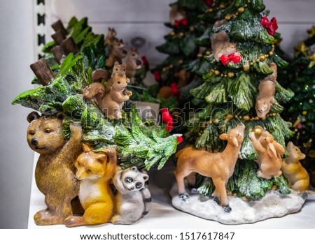Christmas decorations: Figurine of forest animals: bear, Fox, squirrel, raccoon and red bird cardinal, who drag the Christmas tree. On a blurred background-the figure of a Christmas tree with animals