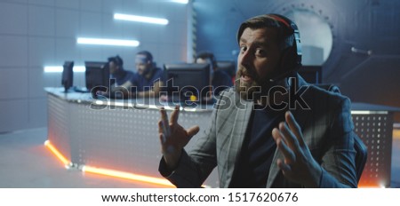 Medium shot of a young bearded man hosting a gaming tournament