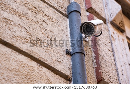 Security cctv cam mounted outside of a building on a wall helps in the video surveillance of the surrounding area. Narrow depth of focus image.