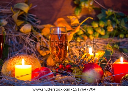 autumn harvest, still life with ripen melon, apple, corn, white vine glass, candle, dry grass and autumn leaves