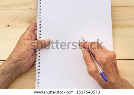 Hands of an elderly man hold a notebook and pen. The concept of writing memoirs, old age and memories. Image. Royalty-Free Stock Photo #1517648570