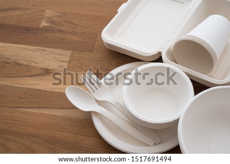 Natural eco-friendly disposable utensils (fork, spoon, dish plate, bowl, cup and fast food box container) made of fiber of bagasse and bamboo on wooden table background with copy space. Save the earth Royalty-Free Stock Photo #1517691494