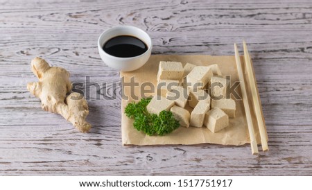 Tofu cheese with ginger root, herbs and soy sauce on a wooden table. Soy cheese. Vegetarian product.