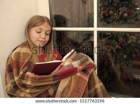 Childrens picture book. Little child read book on Christmas eve. Little girl enjoy reading Christmas story. Little reader in plaid sit on window sill. Magic xmas spirit. The best Christmas book.