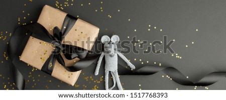 Mouse is a Symbol of new year 2020. Toy mouse and stylish gift box with black bow on black background. New year and Christmas concept. Copy space. Banner