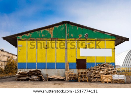 Close-up of the national flag of Gabon
 painted on the metal wall of a large warehouse the closed territory on a summer day. The concept of storage of goods, entry to a closed area, tourism