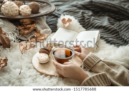 Autumn still life a girl in a warm knitted cozy sweater holding a Cup of tea in the bedroom. Body parts, top view.