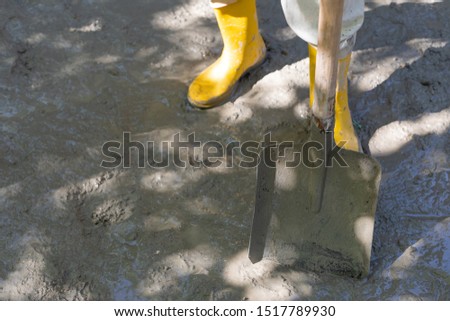 Construction worker in yellow rubber boots at the construction site, compacting the concrete