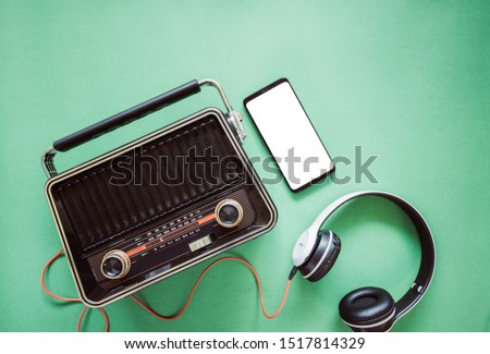 Retro style radio from 1950s, 1960s and headphones, technology mobile phone blank white space for your text on green pastel paper background .Vintage tone instagram style filter photo