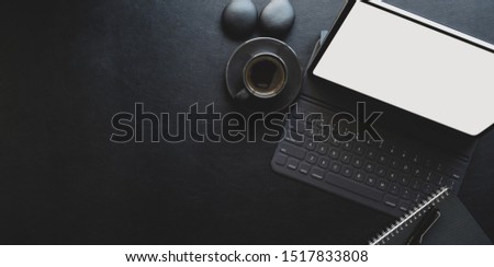 Dark modern workplace with tablet and office supplies on black leather background with copy space