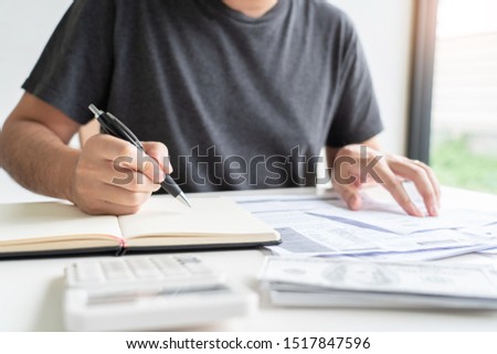 Man using calculator and calculate bills receipt in home expenses payments costs with paper note, financial account management and payment or saving concept
