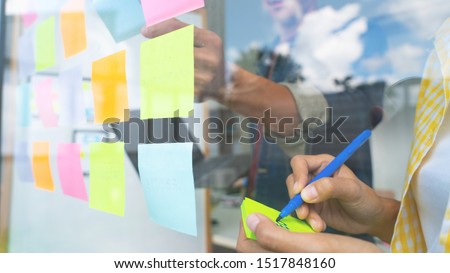 Business people meeting at office and use sticky notes on glass wall in office, diverse employees people group planning work together brainstorm strategy Royalty-Free Stock Photo #1517848160