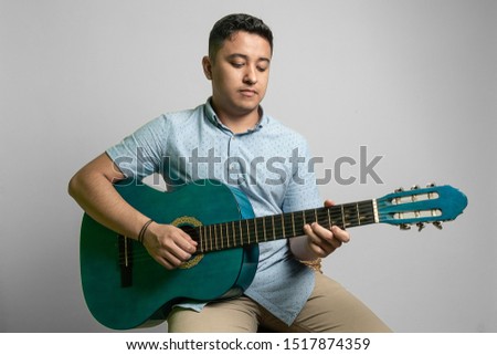 young man playing acoustic guitar on a bench