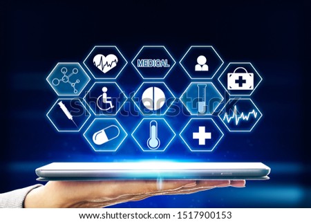 Close up of hand holding tablet with creative medical interface on blue background. Medicine and technology concept