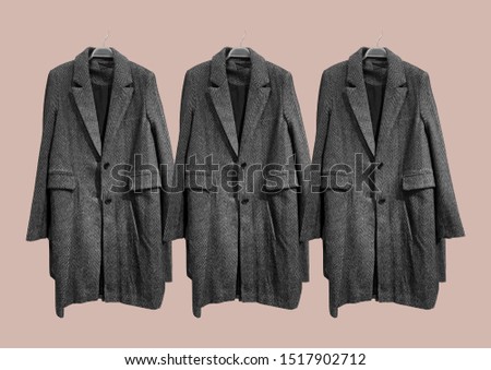 Black and white women coat on hangers isolated on pink background. Composition of clothes. Flat lay, top view, copy space. Ladies' Trench Coat. Winter clothes pattern. Strict classic brown coat