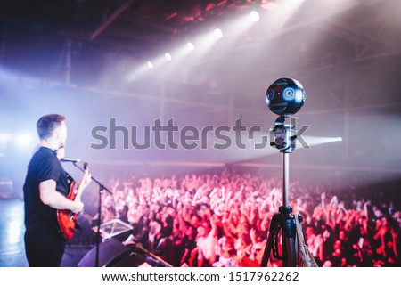 Professional 360 camera at music concert on a tripod recording performance on video.
silhouettes of crowd in front of bright stage lights. Royalty-Free Stock Photo #1517962262