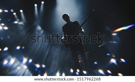 Silhouette of guitar player performinf on concert stage. Dark background, smoke, concert  spotlights