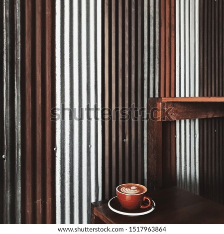 Hot cafe latte art with the metal galvanised background in the industrial coffee shop.