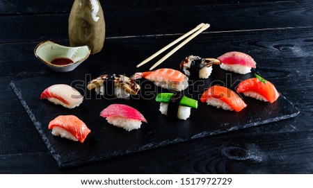 Set of traditional japanese food on a dark background. Sushi rolls, nigiri, raw salmon steak, rice, cream cheese. Asian food frame. Dinner party.